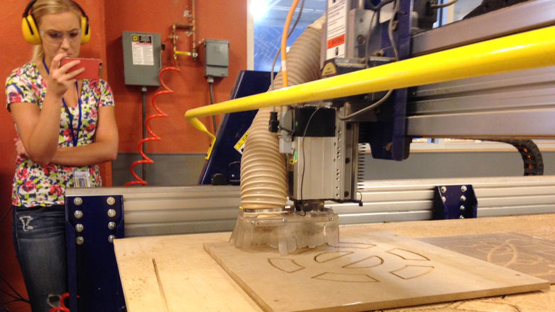 Engineering student Leah Berry records the ShopBot in action with her smart phone.