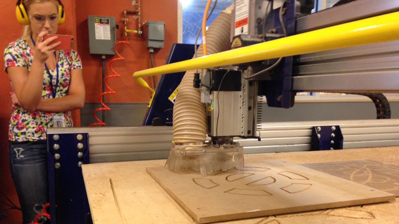 Engineering student Leah Berry records the ShopBot in action with her smart phone.