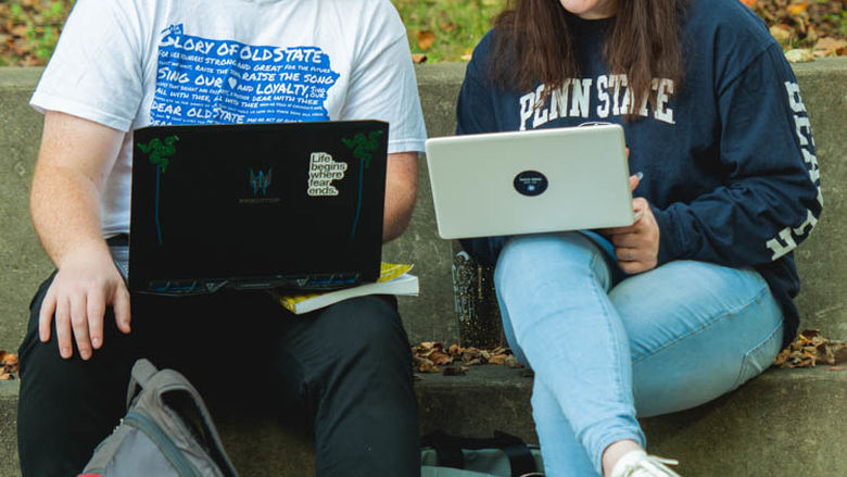 A male student and a female student look at their laptops