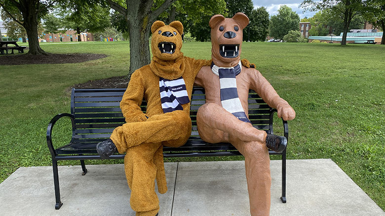 The Nittany Lion sits on the Lion Bench, twinning with his statue, in front of the campus quad