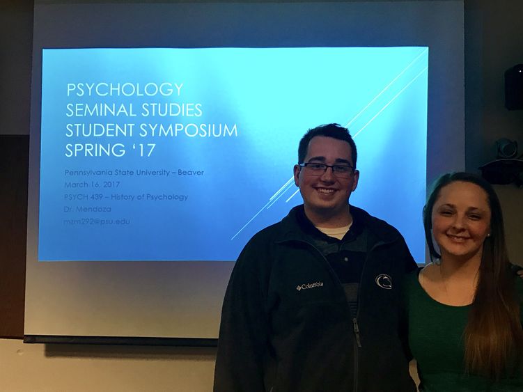 Two of Marissa Mendoza's Psych 439 students pose in front of a screen.