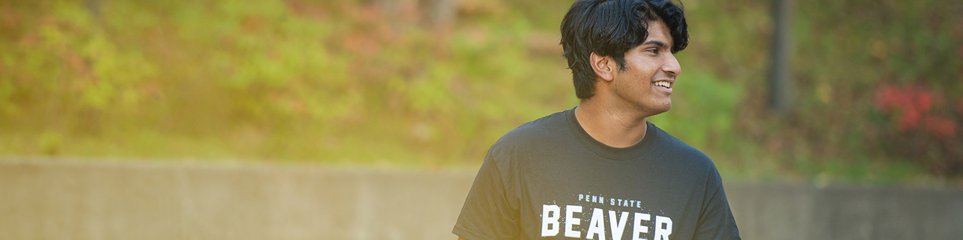 A male student outside wearing a Penn State Beaver t-shirt.