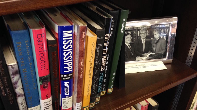A photo of Russ Brignano sits beside books on a shelf.