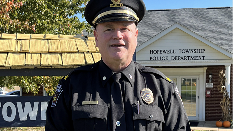 Sedlacek is wearing his police uniform and standing in front of a municipal building.