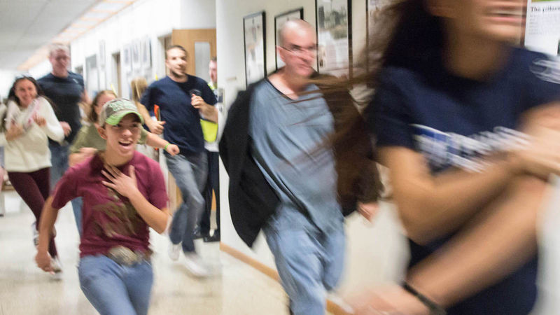 Student actors run down a hallway.