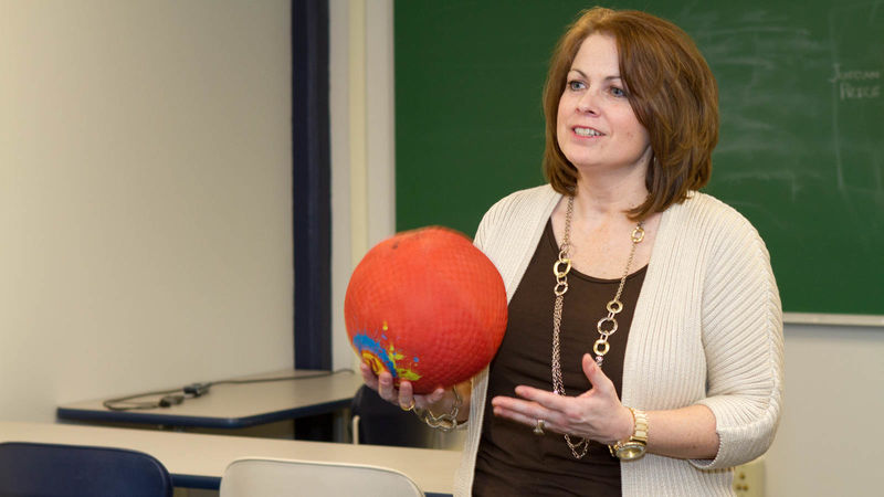 Michelle Kurtyka holds a ball in a classroom in the gymnasium