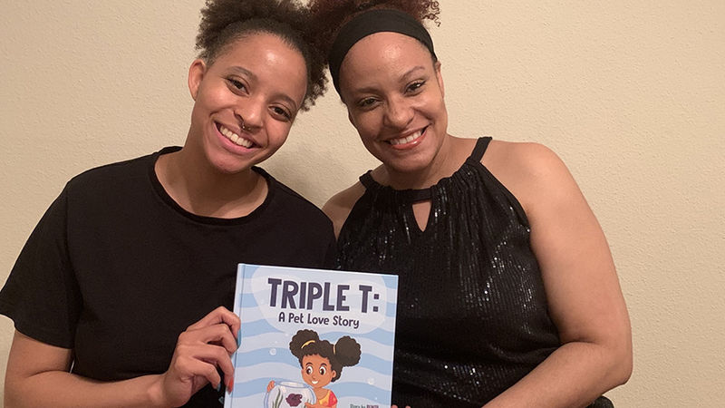 Maria, sitting at left, and her mother Benita, hold a copy of their children's book.