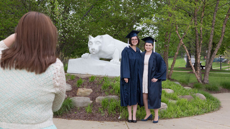 Jessica Findling and a friend pose in their caps and gowns in front of the Lion Shrine.