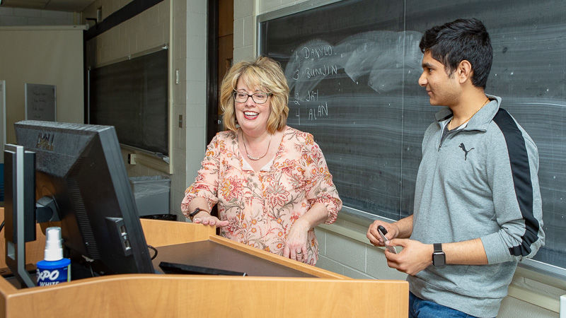 Tiffany MacQuerrie helps a student at the podium in her classroom.