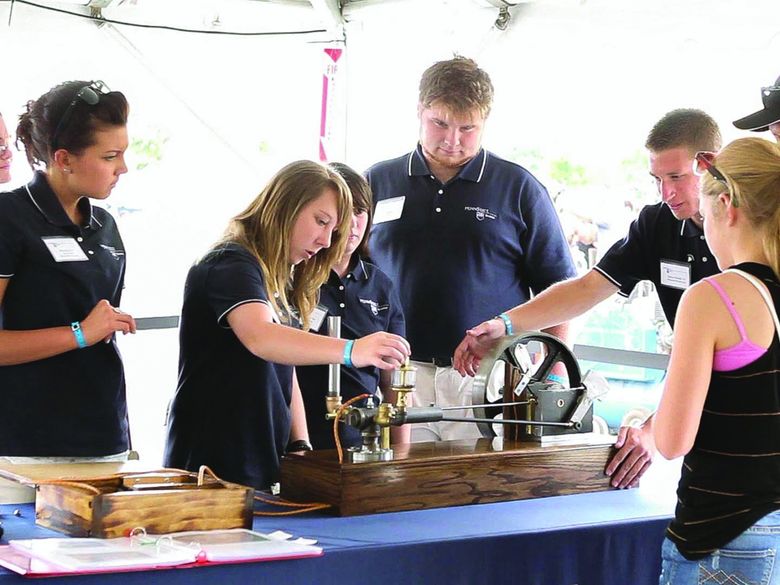 Students display a model of Henry Ford's first engine at Maker Fair Detroit.