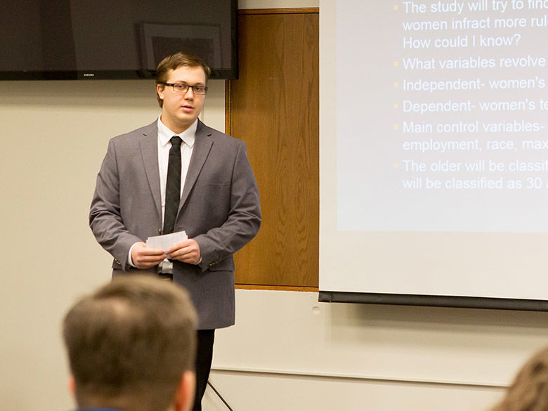 A male student wearing a suit gives a presentation