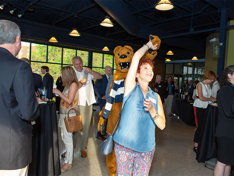 Cathy Ross dances with the Nittany Lion during the annual wine tasting.