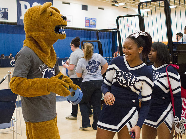 Cheerleaders hang out with the Nittany Lion at a basketball game