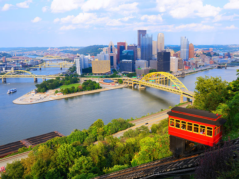 A trolley car goes down the Duquesne Incline. The Pittsburgh skyline is in the distance.