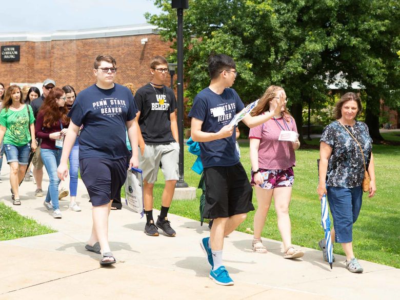 A group of prospective students and their parents tour campus on a sunny summer day.
