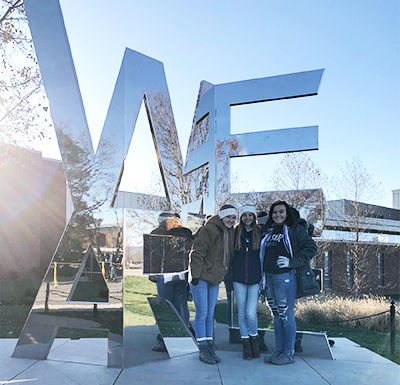 three students pose at the We Are statue
