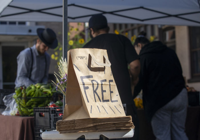 A paper bag labeled "Free Food" sits in front of a stall of fresh produce