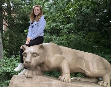 Lauren Lyons poses on the Nittany Lion Shrine at University Park.