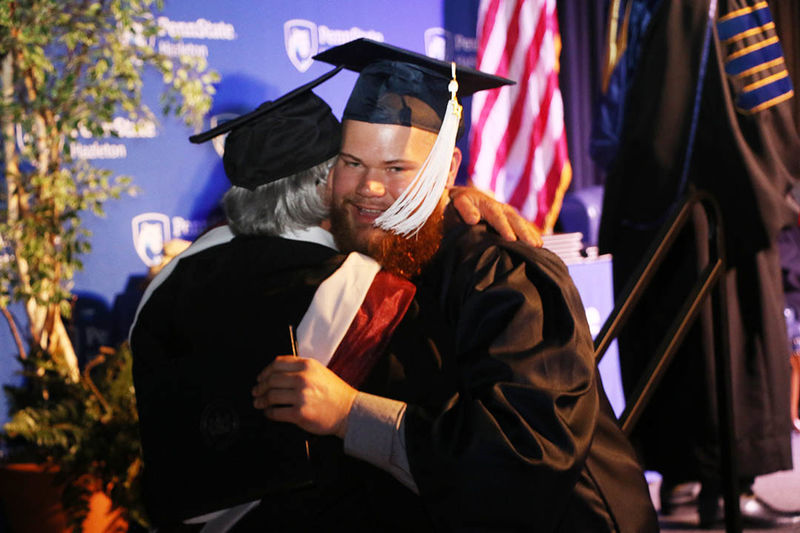 Graduate hugging professor during commencement ceremony. 