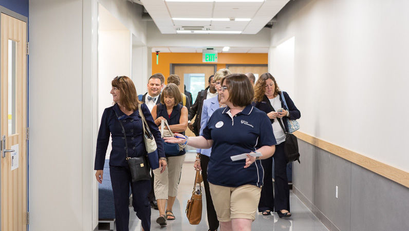 A Lion Ambassador leads a group of alumni through the Michael Baker hallway.