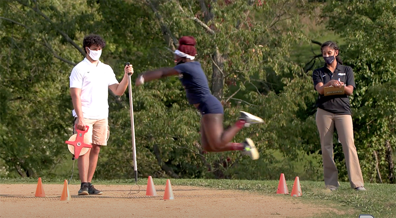 A female athlete leaps through the air during a long jump competition. 