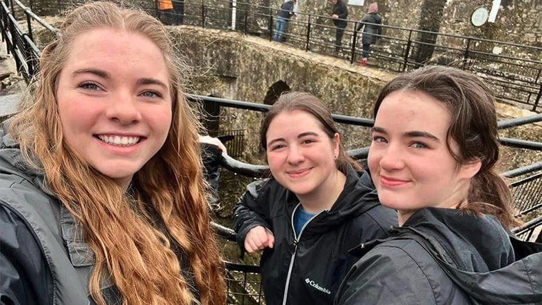 A group of female students stand in a courtyard at Blarney Castle.
