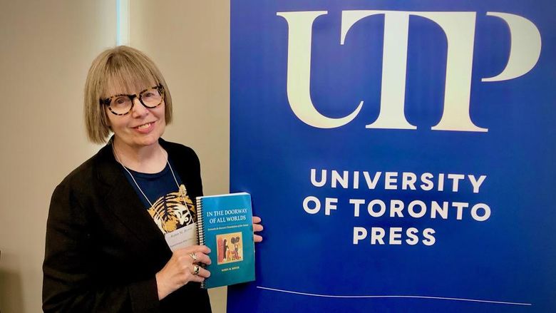 Robin Bower stands with her book in front of a UTP sign
