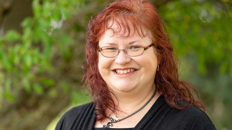 A photo of Gill taken outside. She is smiling and wearing a black jacket.