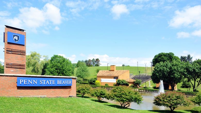 Campus entrance sign with pond and amphitheater in background.