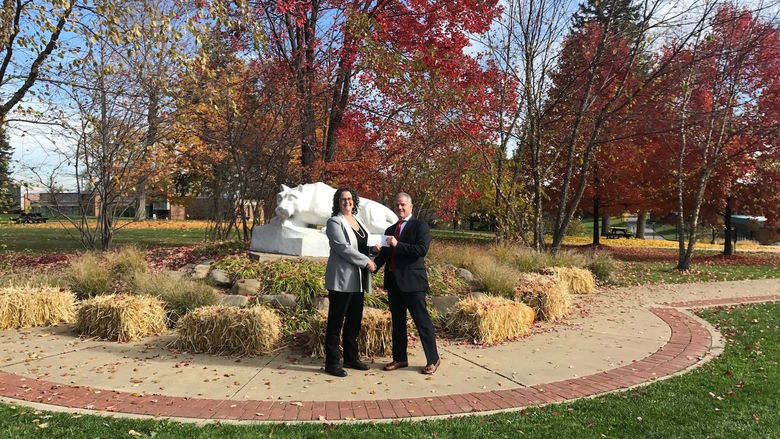 The Penn State Beaver chancellor and Lincoln Learning Solutions CEO shake hands in front of the Lion Shrine.