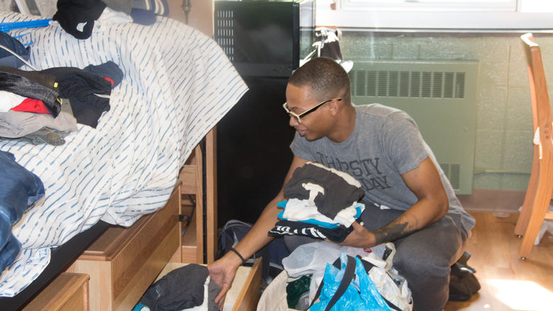Freshman Naiim McClary puts clothes into a drawer under his bed.