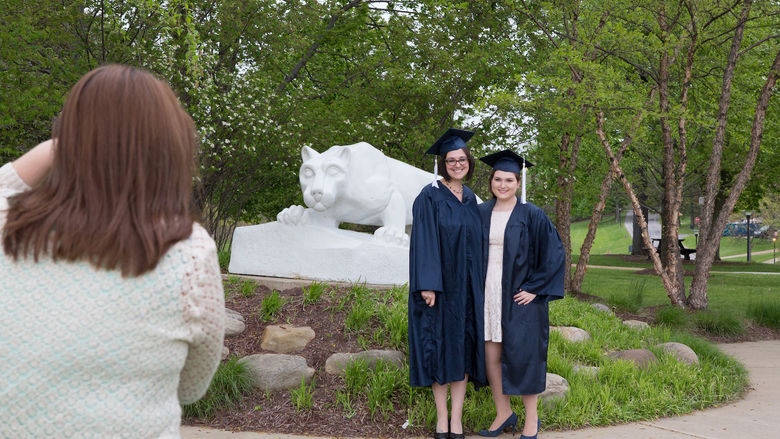 Jessica Findling and a friend pose in their caps and gowns in front of the Lion Shrine.