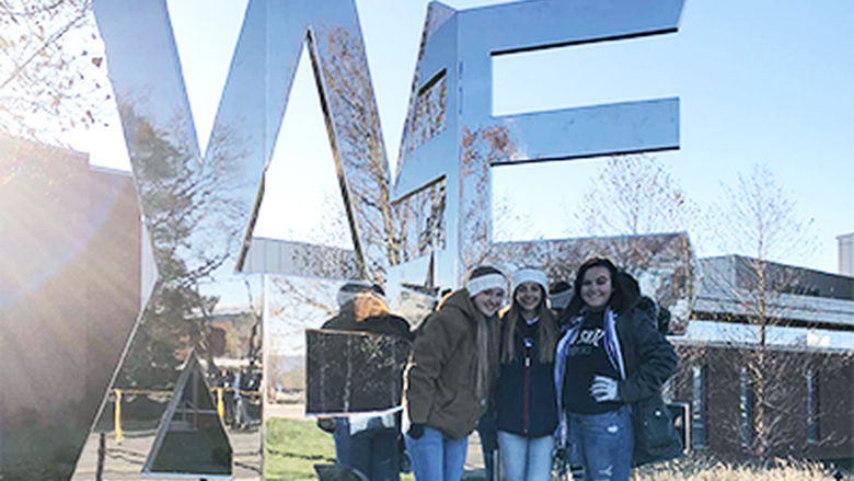 three students pose at the We Are statue