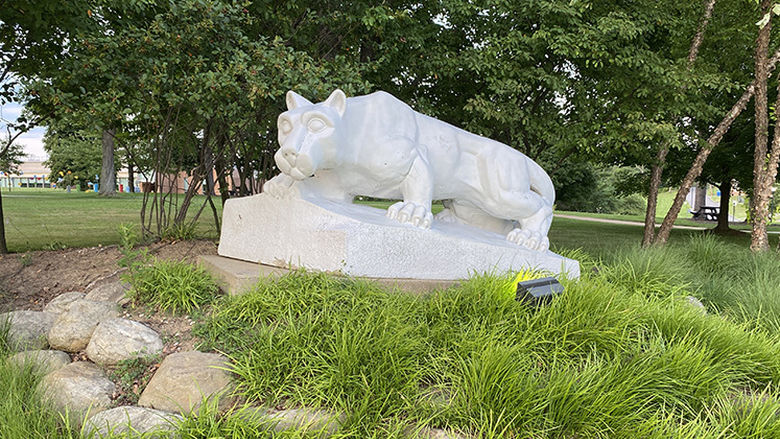 The Nittany Lion shrine sits among greenery in front of the campus quad