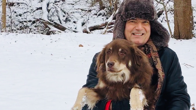 Person holding a dog with snow visible in the background