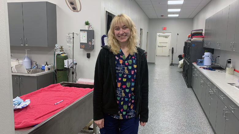 A photo of Cora wearing scrubs in a veterinary office