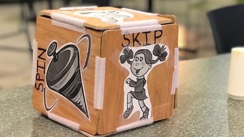 A wooden block held together by velcro and decorated with clip art sits on a table.