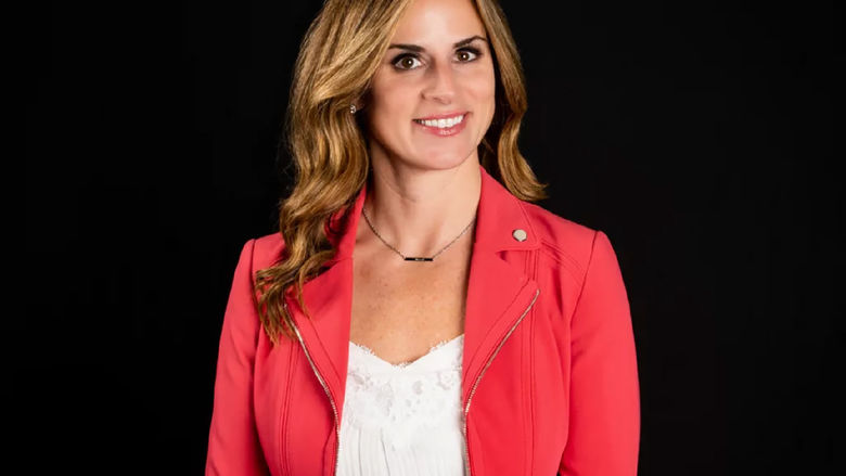 A photo of Dr. Zona wearing a red jacket in front of a black background