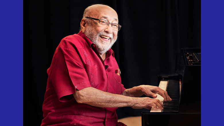 Eddie Palmieri smiling and playing the piano