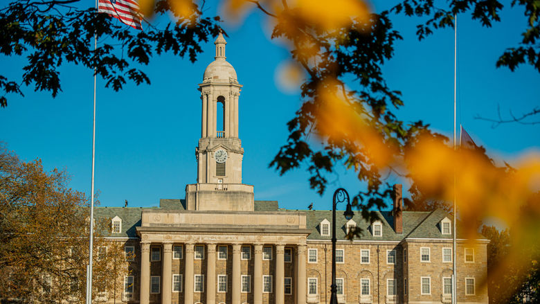 Stone campus building with fall foliage in foreground