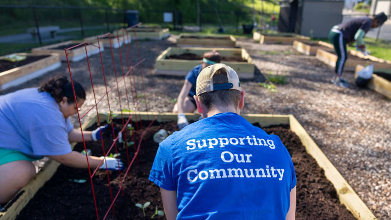 Volunteers in blue Penn State shirts help to set up and maintain a community garden