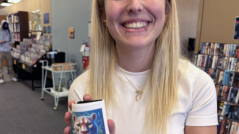 A student holds a coffee mug with a lion design on it