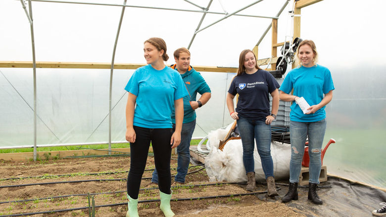 4 students stand in the high tunnel