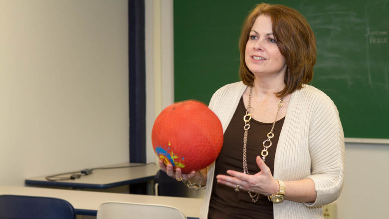 Michelle Kurtyka holds a ball in a classroom in the gymnasium