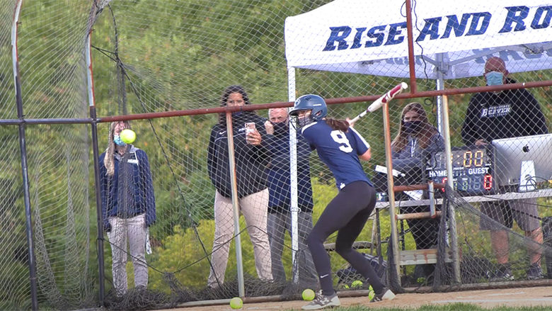 A female softball player stands at bat ready for a pitch.