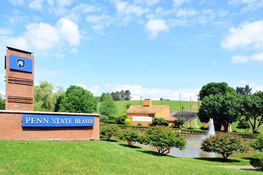 Campus entrance sign with pond and amphitheater in background.