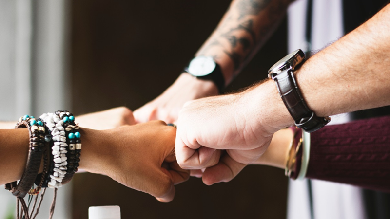 A group of fisted hands joining together.