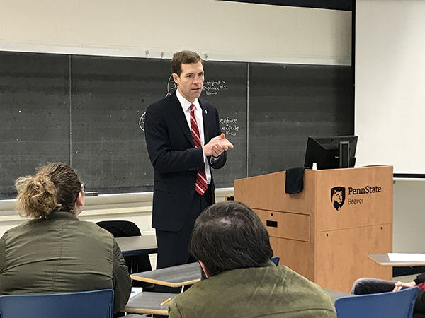 Conor Lamb, wearing a dark blue suit, stands in front of a class of students.