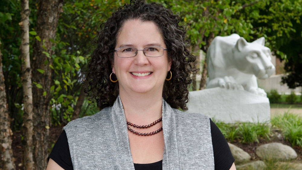 Beaver Chancellor Jenifer Cushman stands in front of the campus Lion Shrine.