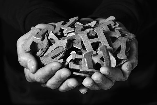 A black and white photos shows cupped hands holding wooden letters